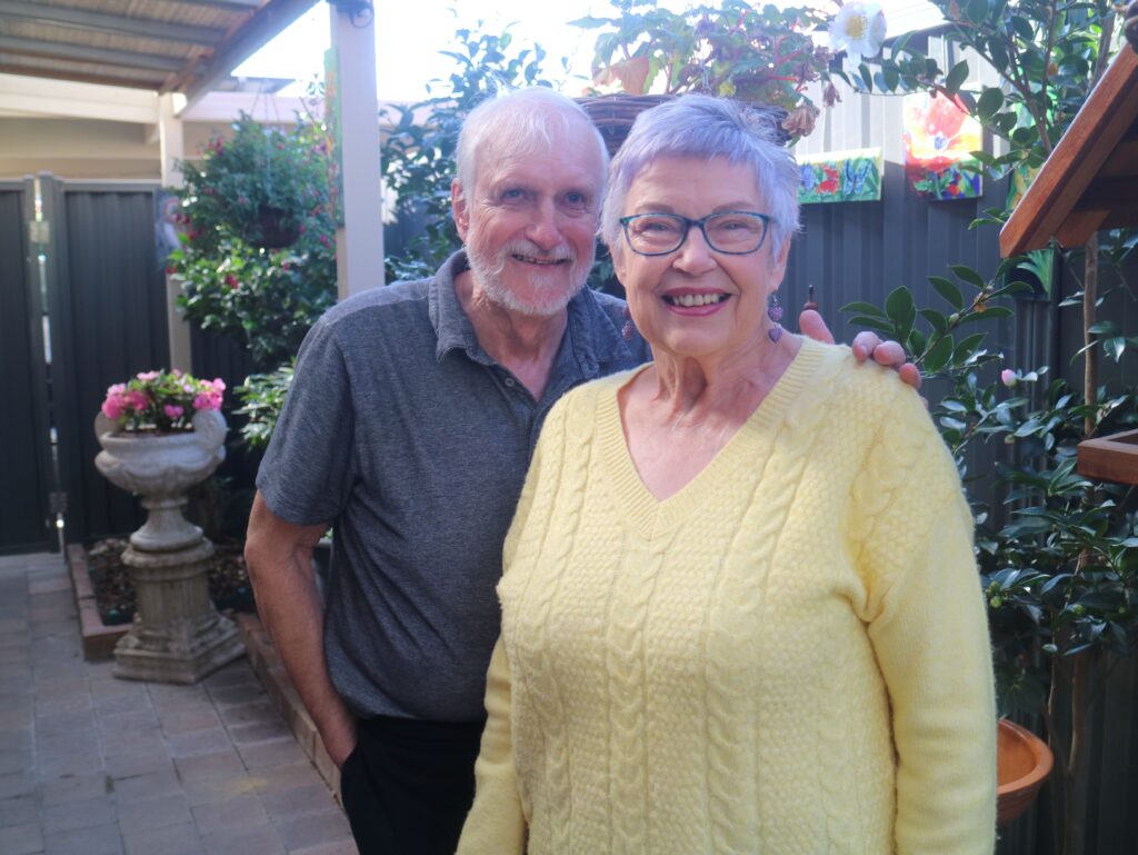 Leigh and his wife, Linda, smiling together outside their home