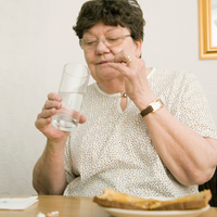 Woman living with Parkinson's takes her medications after meal