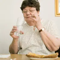 Parkinson's medication management: Woman living with Parkinson's takes her medications after meal