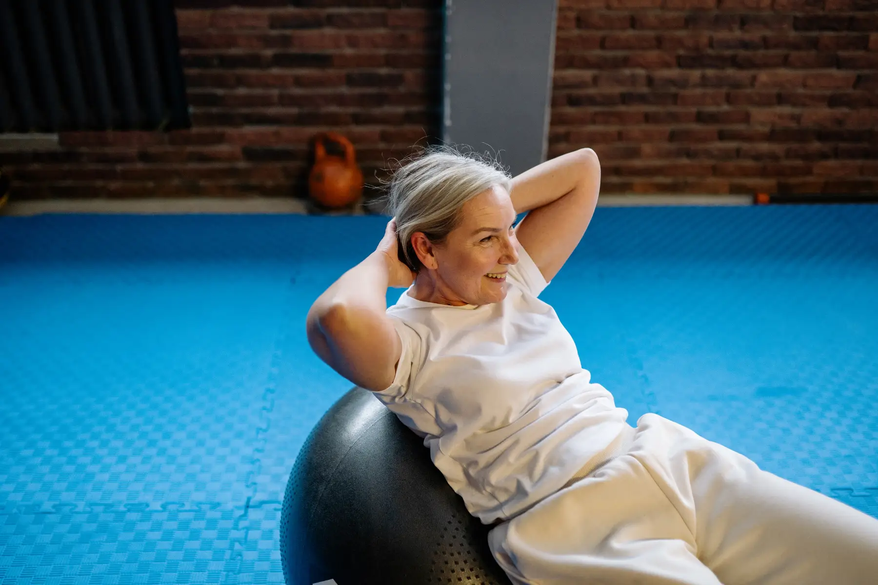 A middle-aged woman performing an ab exercise on an exercise ball