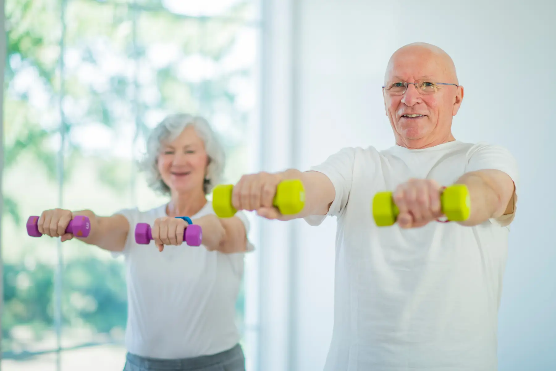 A middle-aged man and woman exercising with dumbbells