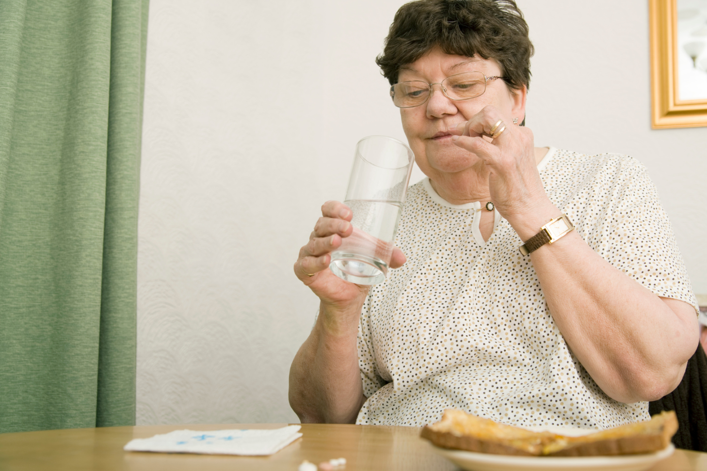 Woman living with Parkinson's takes her medications after meal