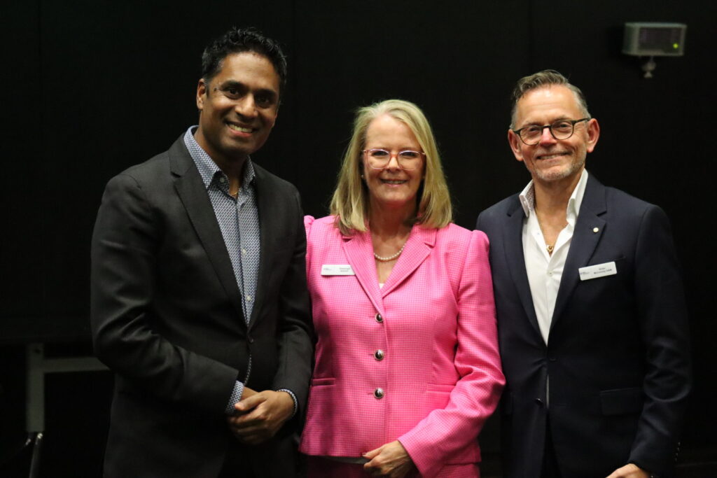 Dr Kishore Kumar, Sheenagh Bottrell, and Victor McConvey standing together indoors at the Fight Parkinson’s 2025 Research Symposium. They are wearing formal attire, including a bright pink blazer and dark suits, with name badges visible, representing speakers and contributors to discussions on Early and Young Onset Parkinson’s research and lived experiences.