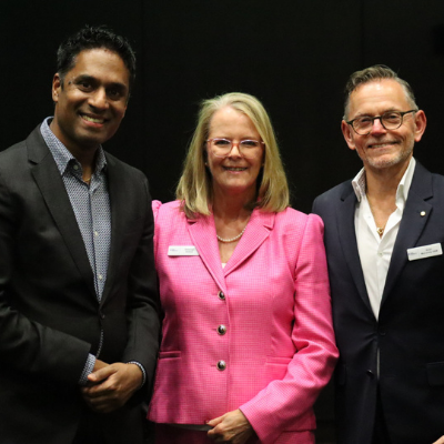 Dr Kishore Kumar, Sheenagh Bottrell, and Victor McConvey standing together indoors at the Fight Parkinson’s 2025 Research Symposium. They are wearing formal attire, including a bright pink blazer and dark suits, with name badges visible, representing speakers and contributors to discussions on Early and Young Onset Parkinson’s research and lived experiences.