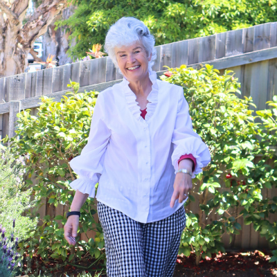Wendy joyfully walking through a manicured garden in her backyard