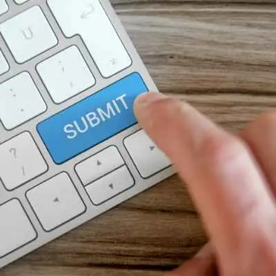 Stock photo image of a hand hovering a submit button on a keyboard